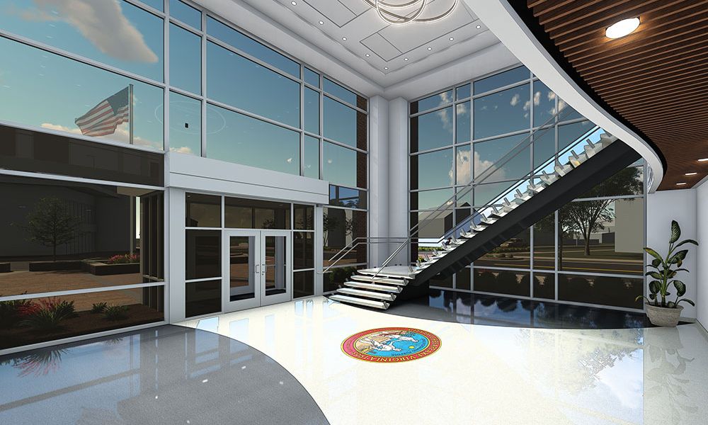 Modern office lobby with large windows, staircase, and American flag outside. Sleek interior design with natural light.